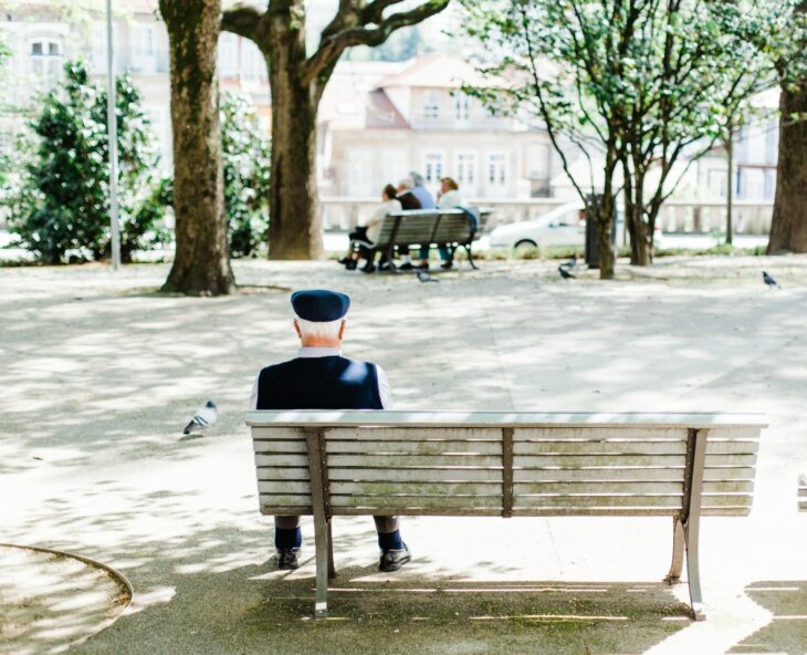person sitting on beige street bench near trees